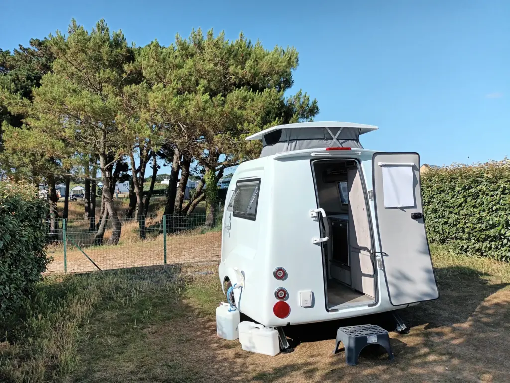 Go-Pod with its rear door open on a pitch beside pine trees